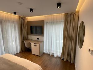 a bedroom with a bed and a desk and curtains at Sidharta Resort in Obarsia-Lotrului