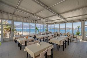 ein Restaurant mit Tischen und Stühlen in einem Raum mit Fenstern in der Unterkunft Hotel Azzurro in Herceg-Novi
