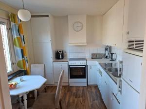a kitchen with white cabinets and a sink and a table at Villa Glumslov in Landskrona