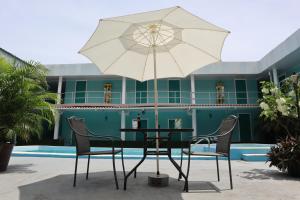 a table and chairs with an umbrella in front of a building at Pacific Coast Hotel in Playa Bonita Village