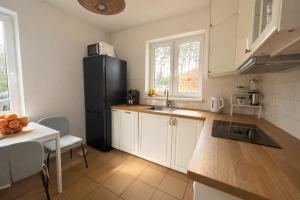 a kitchen with white cabinets and a black refrigerator at Domek na Morskiej in Jantar +17 photos