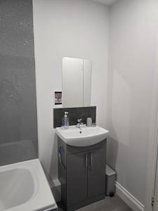 a white bathroom with a sink and a mirror at Antrim Holiday Apartment in Ramsey +4 photos