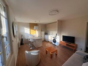 a living room with a couch and a kitchen at Appartement Moderne & Spacieux - 5 min de la mer in Wimille