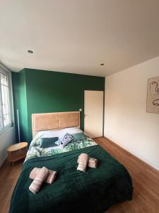 a green bedroom with a bed with three pillows on it at Appartement Moderne & Spacieux - 5 min de la mer in Wimille