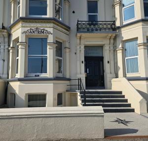 a white building with a black door and stairs at Antrim Holiday Apartment in Ramsey