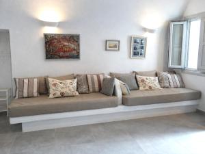 a couch in a living room with pillows on it at Yposkafo Suites - Villa - Santorini in Fira +23 photos