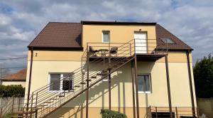 a yellow house with a staircase in front of it at Aurum Vendégház in Esztergom