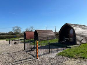 two small huts in a field behind a fence at Poplars Farm Site Glamping Pods Adults only with separate, private shower rooms in Hulland