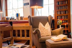 a living room with a chair and a book at Hotel Standlhof Zillertal in Uderns