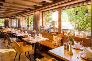 a restaurant with tables and chairs and windows at Hotel Standlhof Zillertal in Uderns