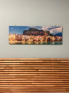 a painting hanging on a wall above a wooden bench at Studio Osnao Historic City Center in Cefalù