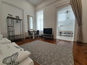 a living room with a bed and a table and a television at Déri Kert Apartmanház A in Baja