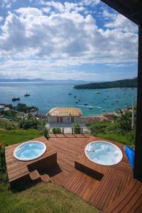 two hot tubs on a wooden deck with a view of the water at Marques Home in Porto Belo