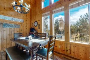 a dining room with a table and chairs and windows at Eagle Creek Chalet on the Pond in Redmond