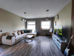 a living room with a white couch and a tv at Kusagil Nature & Sauna near Pärnu in Tahkuranna