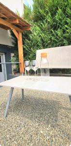 a white bench with two glasses and a bottle on it at Côté cour, T2 espace exterieur au calme in Lourdes