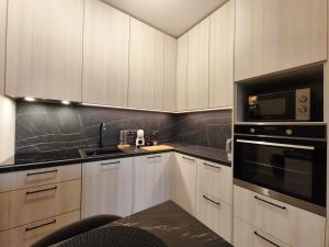 a kitchen with white cabinets and black counter tops at Kusagil Nature & Sauna near Pärnu in Tahkuranna +14 photos