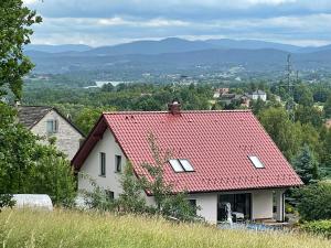 a white house with a red roof on a hill at Noclegi Bajama in Siepraw