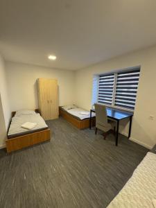 a room with two beds and a desk and a table at Beregi Apartman II in Mezőcsát