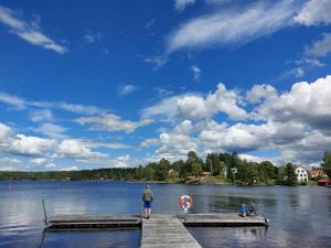 a man standing on a dock on a lake at Glamping Tolvsbo Inn in Söderbärke