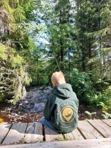 a man is sitting on a wooden bridge while fishing at Glamping Tolvsbo Inn in Söderbärke