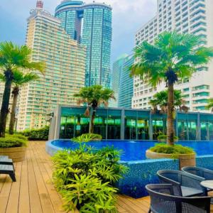 a pool with palm trees in a city with buildings at Vortex Apartment klcc by HouseFull in Kuala Lumpur
