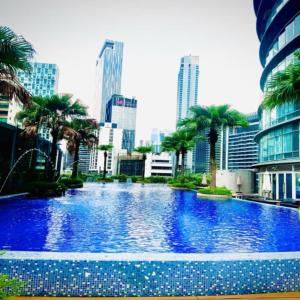 a large swimming pool with palm trees in a city at Vortex Apartment klcc by HouseFull in Kuala Lumpur