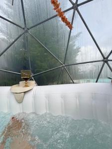a bath tub with a glass dome with a drink and a candle at Monte do Bidé Private Farm Peace and Nature in Setúbal