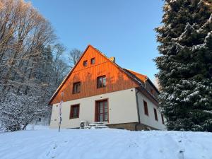 a house with an orange roof in the snow at Chalupa Bišík in Teplice nad Metují