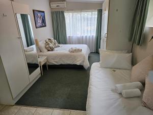 a hotel room with two beds and a mirror at Leopards Tree Garden Cottage in Greytown