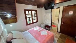 a bedroom with a bed with a table and a bathroom at Villaggio Farnese in Campos do Jordão