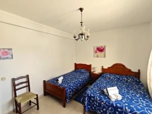 a bedroom with two beds and a chair and a chandelier at Pacheco's Guesthouse in Lagos