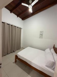 a bedroom with a bed with a ceiling fan at Casa luzes Amarelas in Caraguatatuba