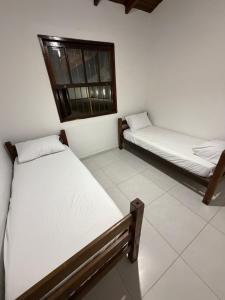 two beds in a room with a window at Casa luzes Amarelas in Caraguatatuba +1 photo