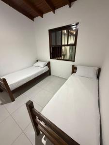two beds in a room with a window at Casa luzes Amarelas in Caraguatatuba