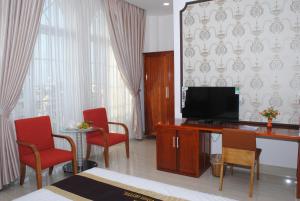 a hotel room with a television and red chairs at Tran Vinh Hotel in Bạc Liêu