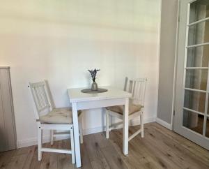 a white table with two chairs and a vase with flowers at Ferienwohnung Muranko in Bad Doberan