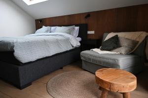 a bedroom with a bed and a couch and a chair at Cetti's Lodge - met privé sauna in Nieuwkoop