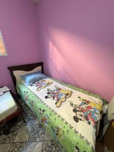 a bed in a bedroom with a purple wall at Quarto com duas camas confortáveis in Belo Horizonte