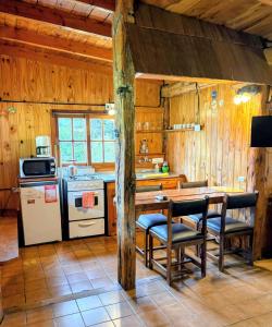 a kitchen with wooden walls and a table and chairs at Cabañas Walnor in Villa Traful