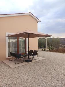 two chairs and an umbrella in front of a house at Vinea Nature in Brkač +10 photos
