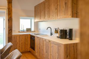 a kitchen with wooden cabinets and a sink at Relax In A Thatched Barn With A Sauna in Ratekau