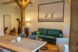 a living room with a green couch and two deer paintings at Relax In A Thatched Barn With A Sauna in Ratekau