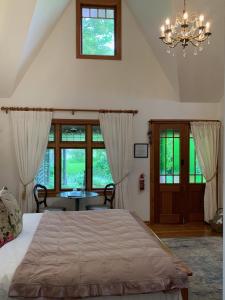 a bedroom with a bed with a chandelier and windows at Quail Farm, Colonial charm in Nelson