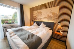 a bedroom with a large bed with a large window at Hotel Berghof in Hellenthal