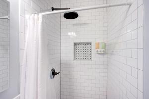 a white tiled shower with a shower curtain at Splendid Colonial in Midtown with Parking in Memphis +17 photos