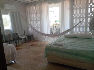 a bedroom with a bed with a hammock in it at POUSADA GOLFINHO FLECHEIRAS Ce in Trairi