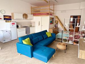 a living room with a blue couch and a kitchen at B&B The Loft in Gioiosa Ionica
