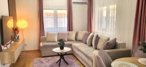 a living room with a couch and two windows at Alma Apartment - Family Stay Across Aqua Park Raj in Vrnjačka Banja