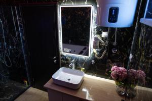 a bathroom with a sink and a mirror and flowers at Foča Apartman STORY LUX in Foča